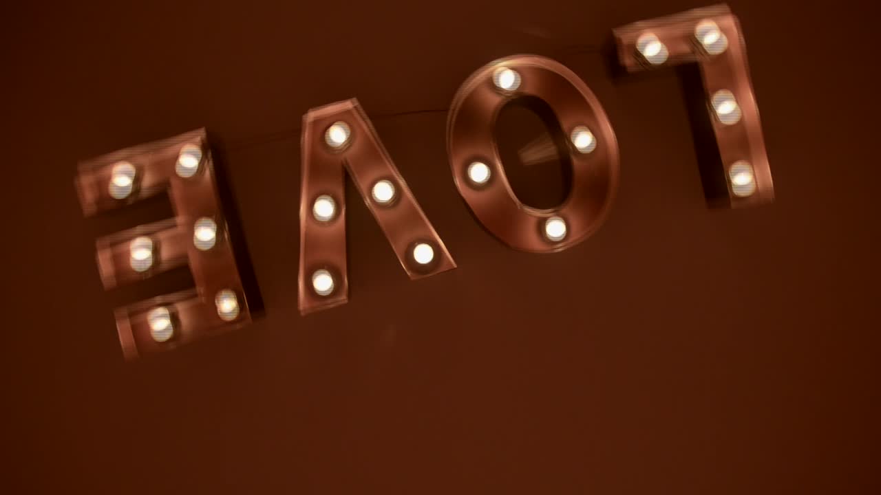 Beautiful lighting love signal hanging on the wall, taken with a transition from close up to a wide shot, while the camera makes a B-roll shot movement like inception movie.