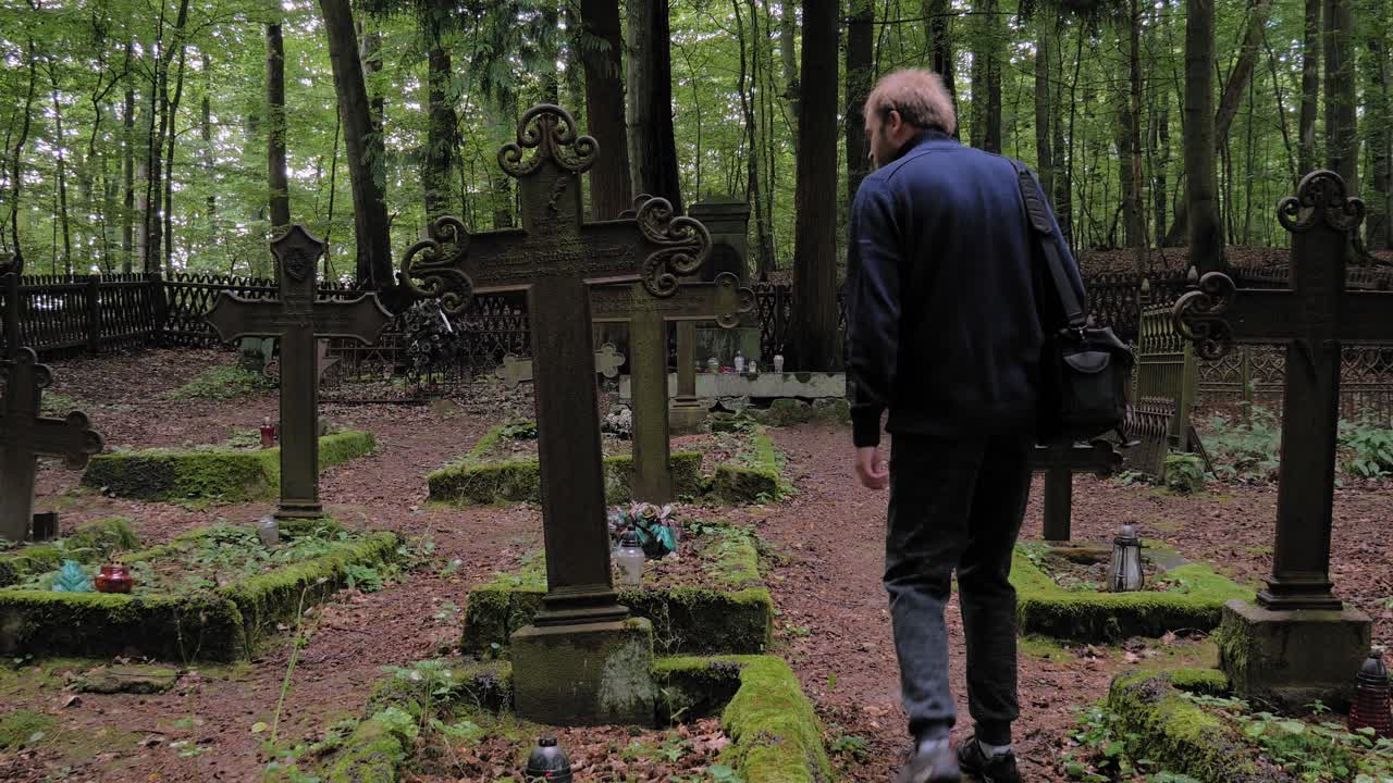 hombre visitando una tumba en el cementerio de pyszno, polonia, donde los silvicultores alemanes fueron enterrados antes de la segunda guerra mundial - tiro completo