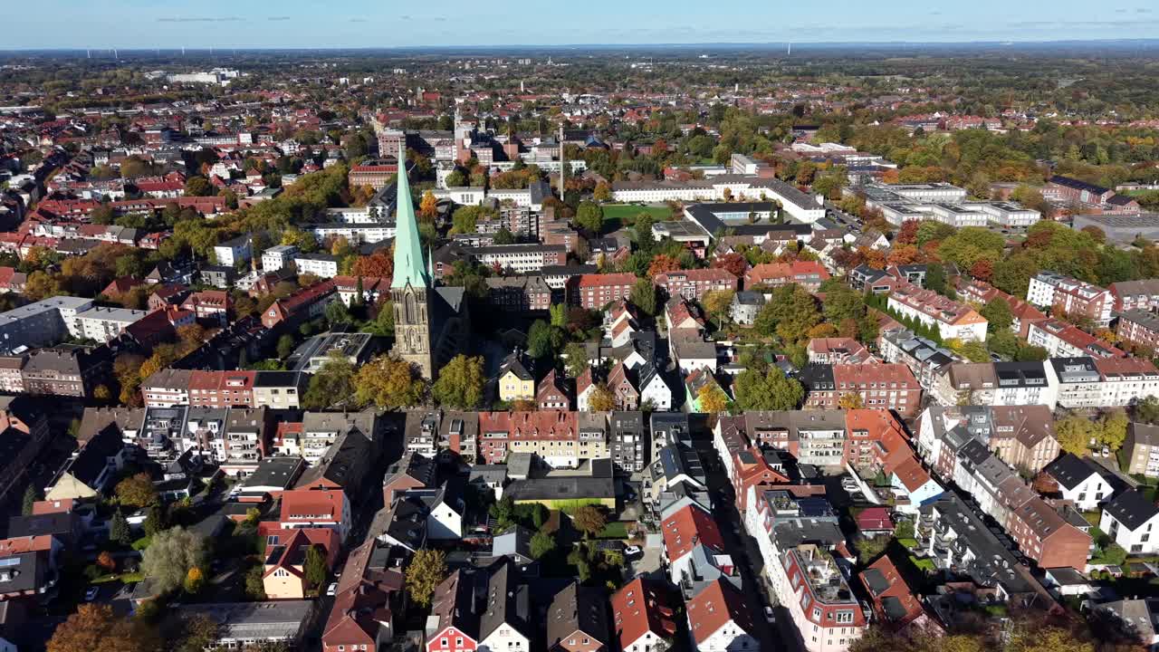 German neighborhood at sunset time with row of houses and townhomes. Church tower of historic church in Münster, Germany. Aerial flyover in autumn season