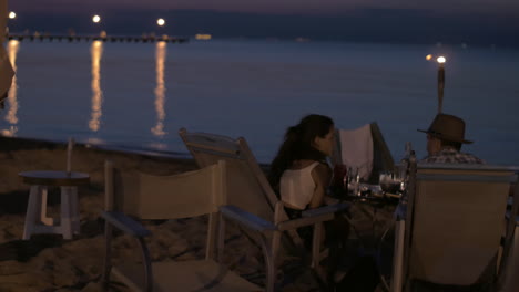 view of young happy couple having romantic dinner on the beach greece