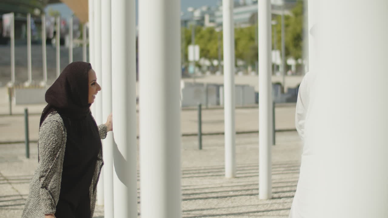 젊은 무슬림 부부가 기둥 사이에 숨어서 놀고 있습니다.