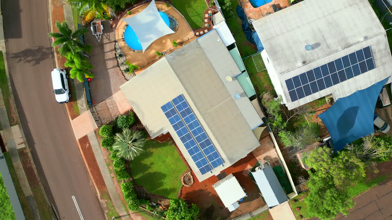 dron aéreo de una casa tropical colorida con paneles solares y piscina en el patio trasero mientras los coches pasan, ascienden de arriba hacia abajo