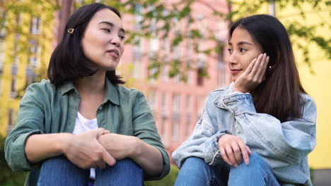 dos chicas japonesas muy jóvenes sentadas y hablando juntas al aire libre 1