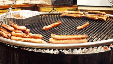 german sausage cooking on hot griddle at city winter food market stall