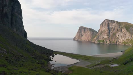 Aerial-shot-of-remote-Lofoten-Sandvika-beach-in-Noway-surrounded-by-steep-cliffs