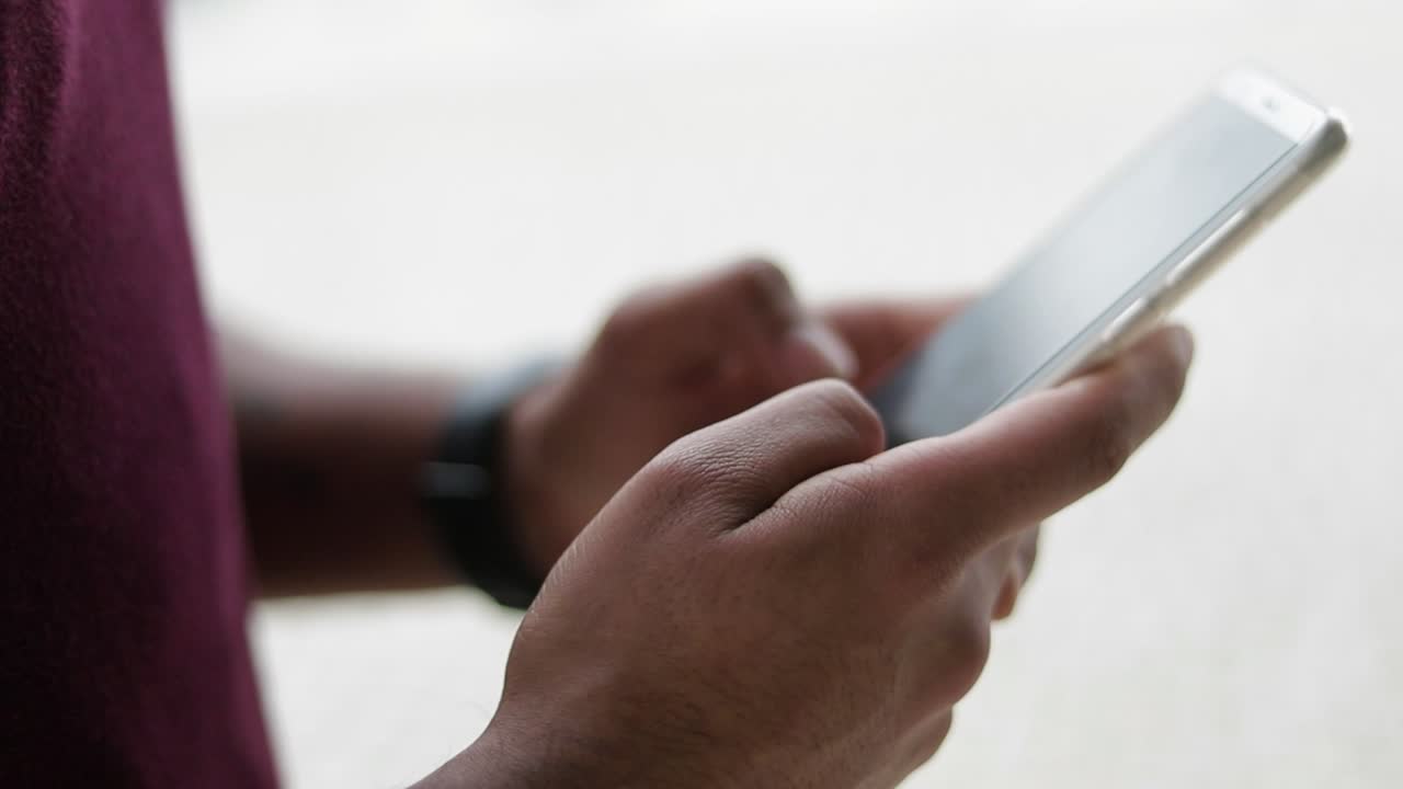 Close up shot of mixed-race male hands texting on phone