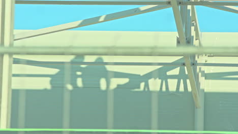 Shot-with-focus-transition-between-a-fence-of-an-industrial-building-and-a-wall-on-which-the-shadows-of-workers-can-be-seen