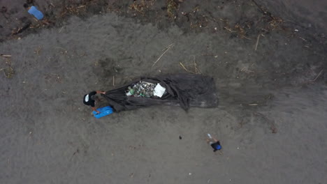 Volunteers-toss-trash-litter-from-beach-cleanup-onto-tarp-on-sand