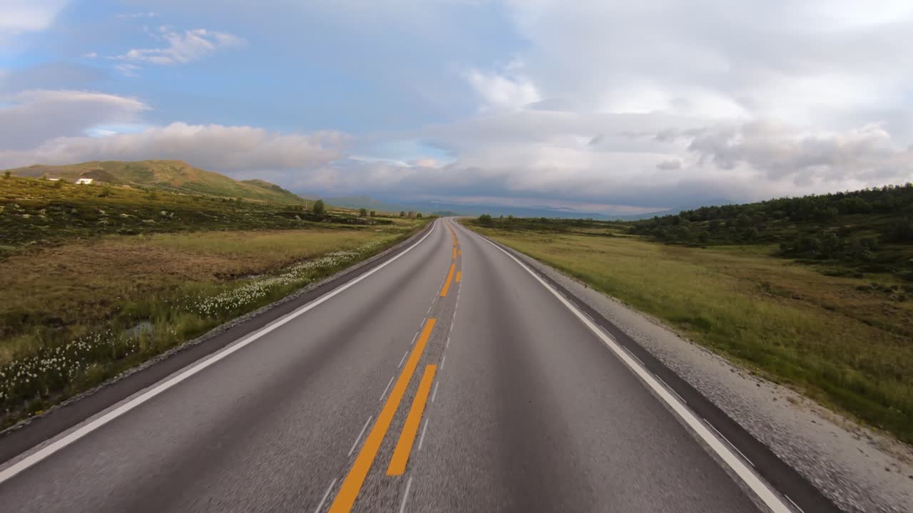 Guida di un'auto su una strada in Norvegia all'alba