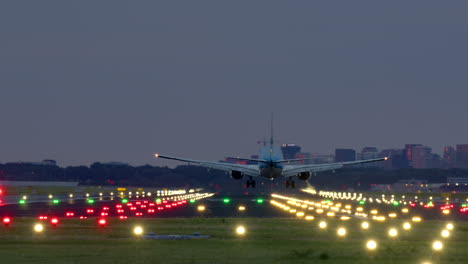 airplane landing at night with city skyline in the background