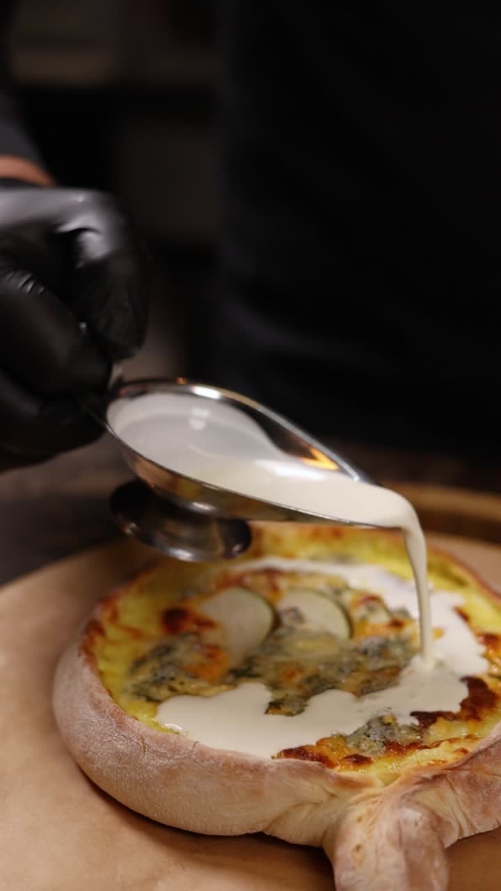 Chef preparing a gourmet pizza with cheese and creamy sauce