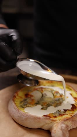 chef preparando una pizza gourmet con queso y salsa cremosa