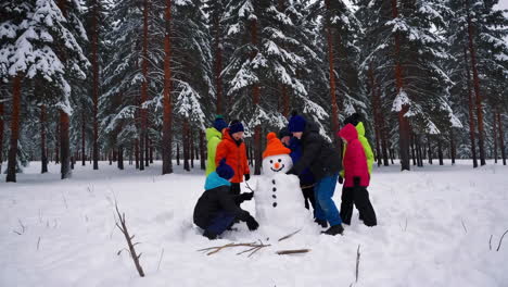 children building a snowman in a snowy winter forest