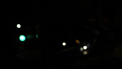 Out-of-focus-beautiful-glittering-blurred-bokeh-of-cars-and-traffic-lights-at-night-through-the-car-rear-view-mirror