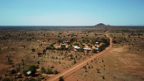 Panoramic-drone-shot-approaching-an-African-village-in-Karamoja,-also-called-Manyattas-in-Uganda-on-a-sunny-day