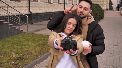 una pareja de turistas caucásicos tomando selfies en la calle.