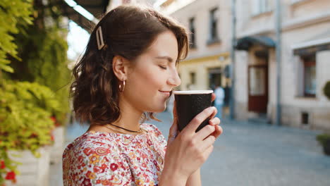 Caucasian-woman-enjoying-drinking-morning-coffee-hot-drink,-relaxing,-taking-a-break-in-city-street