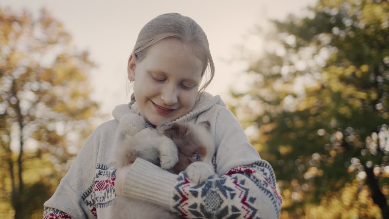 한 아이가 귀여운 작은 강아지를  ⁇ 안고 있다. 해가 지는  ⁇ 에 서 있다.