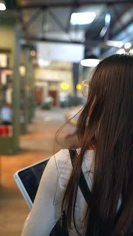 mujer con tableta en una librería