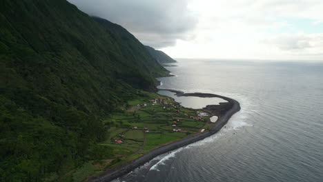 Aerial-view-of-coastal-village-under-tall-and-steep-slope