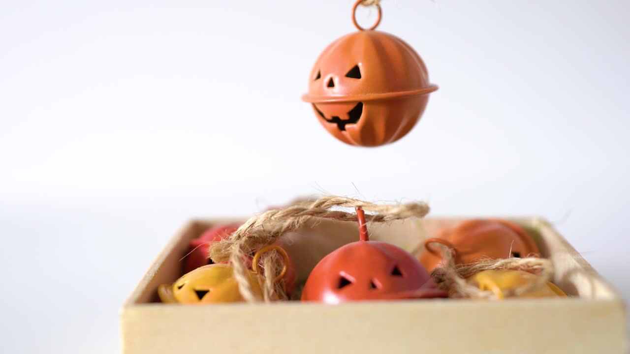 흰색 배경에 격리된 여성의 손에 매달려 있는 주황색 금속 할로윈 얼굴 종