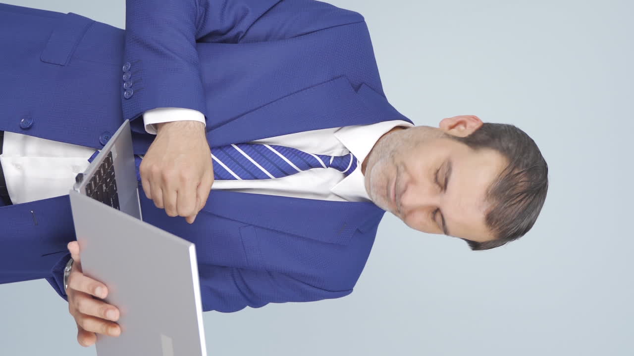 지친 표정으로 노트북을 바라보는 사업가의 수직 비디오.