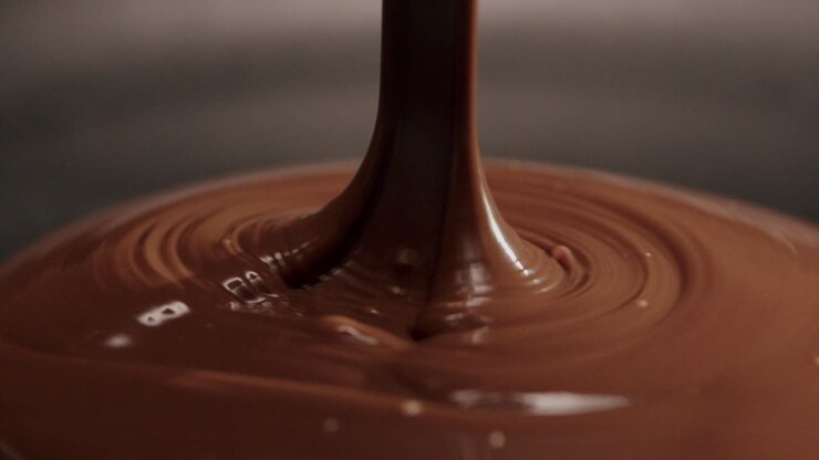 Ripresa al rallentatore di cioccolato al latte fuso che viene versato.