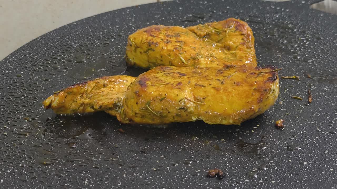 Chicken meat, marinated with spices, is grilled on a flat, non-stick pan. The spices sizzle, releasing a delicious aroma. Close-up shot shows the chicken browning perfectly on the grill
