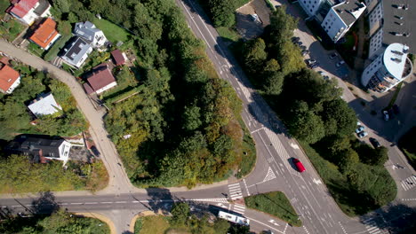 Toma-Aérea-De-Arriba-Hacia-Abajo-De-Un-Autobús-Conduciendo-Por-La-Carretera-Y-Un-Barrio-Polaco-Durante-El-Día-Soleado-En-La-Ciudad-De-Gdynia