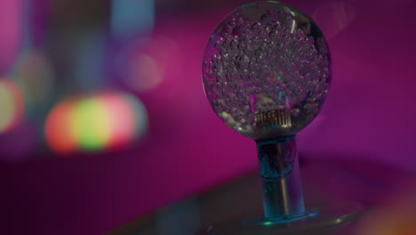 primer plano detallado de la bola de botón de vidrio transparente con burbujas y luces parpadeando desde la feria