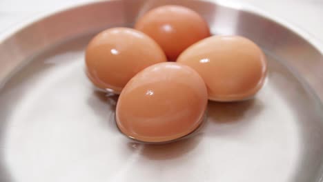 four chicken eggs on the water in the plate