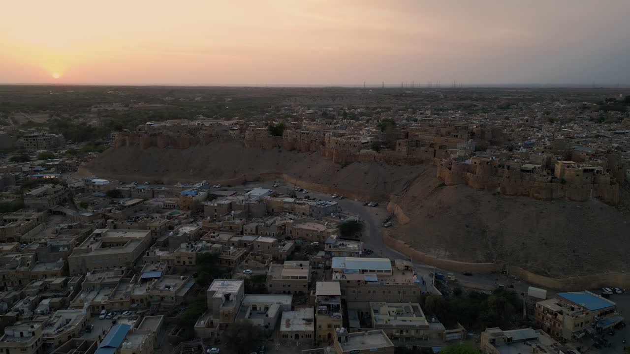 потрясающий 4k дрон орбитальный снимок форта джайсалмер во время захода солнца, с солнцем, раскрывающим за силуэтом форта раджастан индия