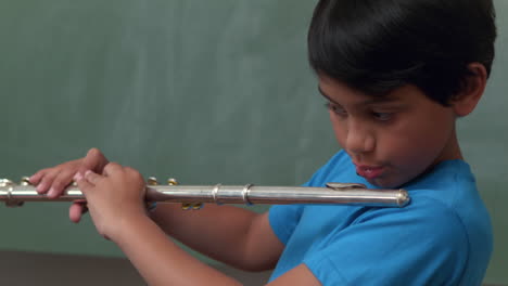 Cute-pupil-playing-flute-in-classroom