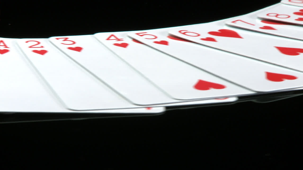 A deck of cards laid out rotates in front of a camera
