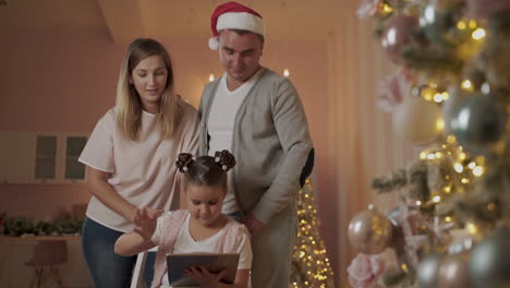 mother, father and little girl having video call at christmas