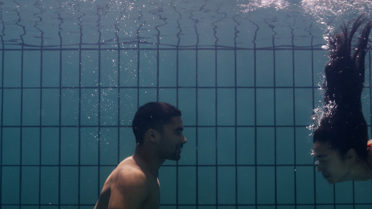 una pareja submarina besándose en la piscina jóvenes enamorados disfrutando de un beso romántico amantes apasionados sumergidos en el agua flotando con burbujas en una intimidad lúdica