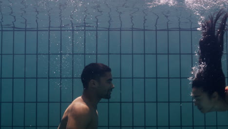 una pareja submarina besándose en la piscina jóvenes enamorados disfrutando de un beso romántico amantes apasionados sumergidos en el agua flotando con burbujas en una intimidad lúdica