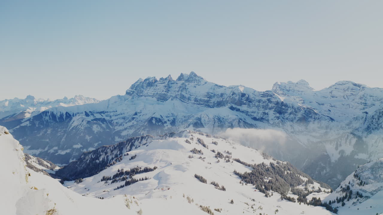 Freeride skier skinning up with Dents du Midi backdrop, then charging steep powder on a bluebird day near Champéry and Avoriaz.