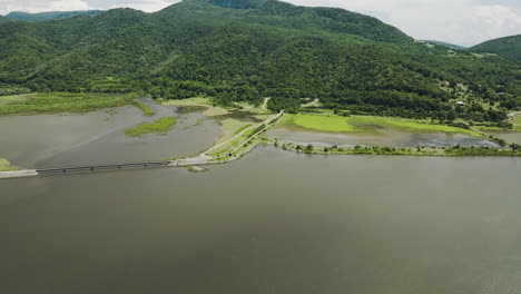 Bridge-over-Tkibuli-lake-reservoir-and-lush-green-shoreline,-Georgia