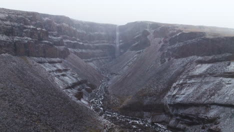 volando sobre el río hengifossa a la cascada hengifoss durante las nevadas en islandia