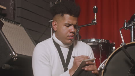 latin man sitting in the recording studio and writing in the notebook