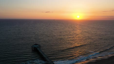 Hora-Dorada-Con-Océano-Sereno-En-El-Muelle-De-La-Playa-De-Manhattan-Con-Acuario-De-Casa-Redonda-En-California,-Estados-Unidos