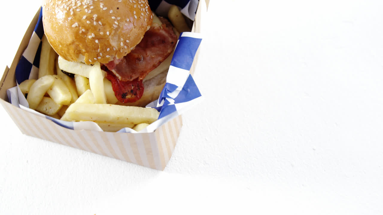 hamburguesa y papas fritas en un contenedor para llevar en la mesa