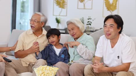 A joyful family shares a moment on the couch with popcorn, highlighting warmth and togetherness in a cozy living room