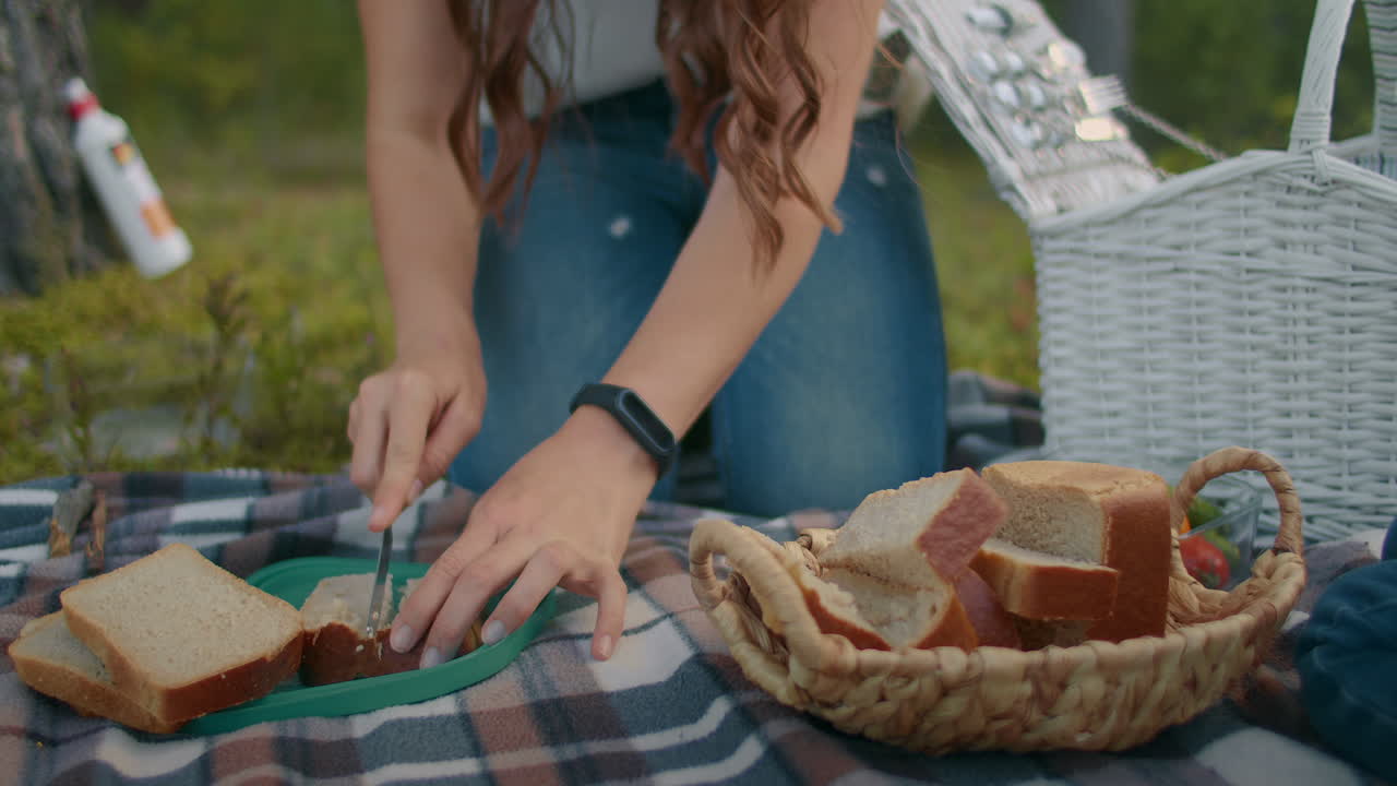 picnic en el bosque mujer joven está cortando pan para la familia o amigos fin de semana en la naturaleza en verano