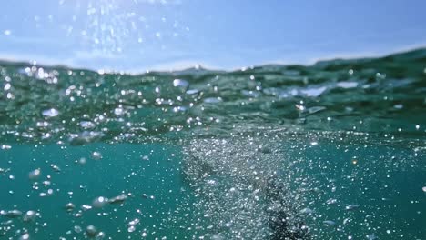 Vista-Trasera-Submarina-Dividida-De-Un-Hombre-Adulto-Nadando-Con-Aletas-De-Buceo-En-Agua-De-Mar-Cristalina