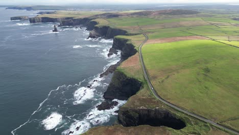 wide aerial drone shot above the coastal farm fields of the kilkee cliffs ireland countryside