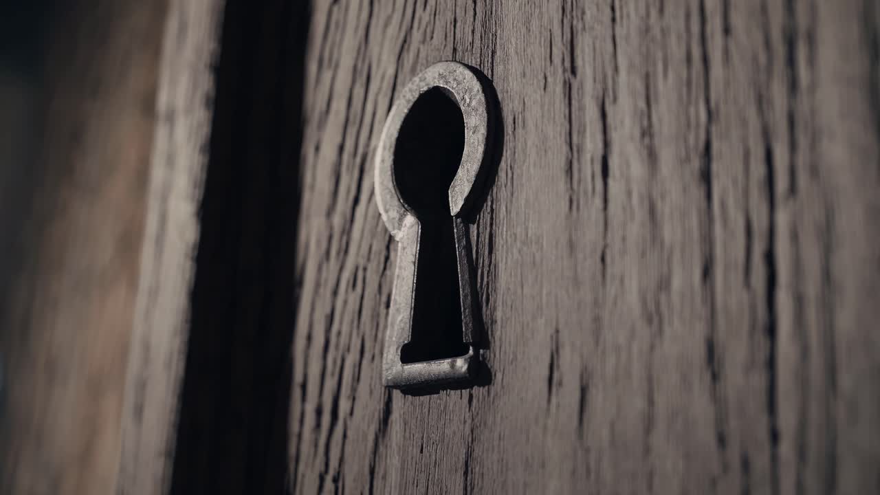 Close-up video shot of a rustic wooden door with a vintage keyhole, captured at an angled