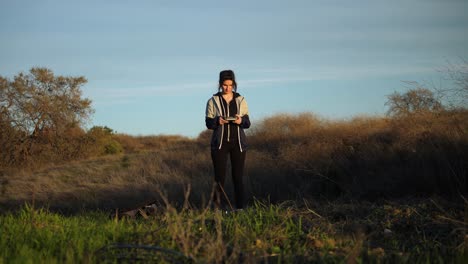 girl taking off small drone into the sky out in nature