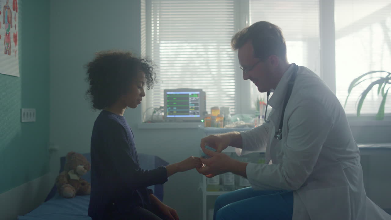 Pediatra usa un ossimetro per controllare la saturazione di ossigeno sul dito di una bambina in primo piano.